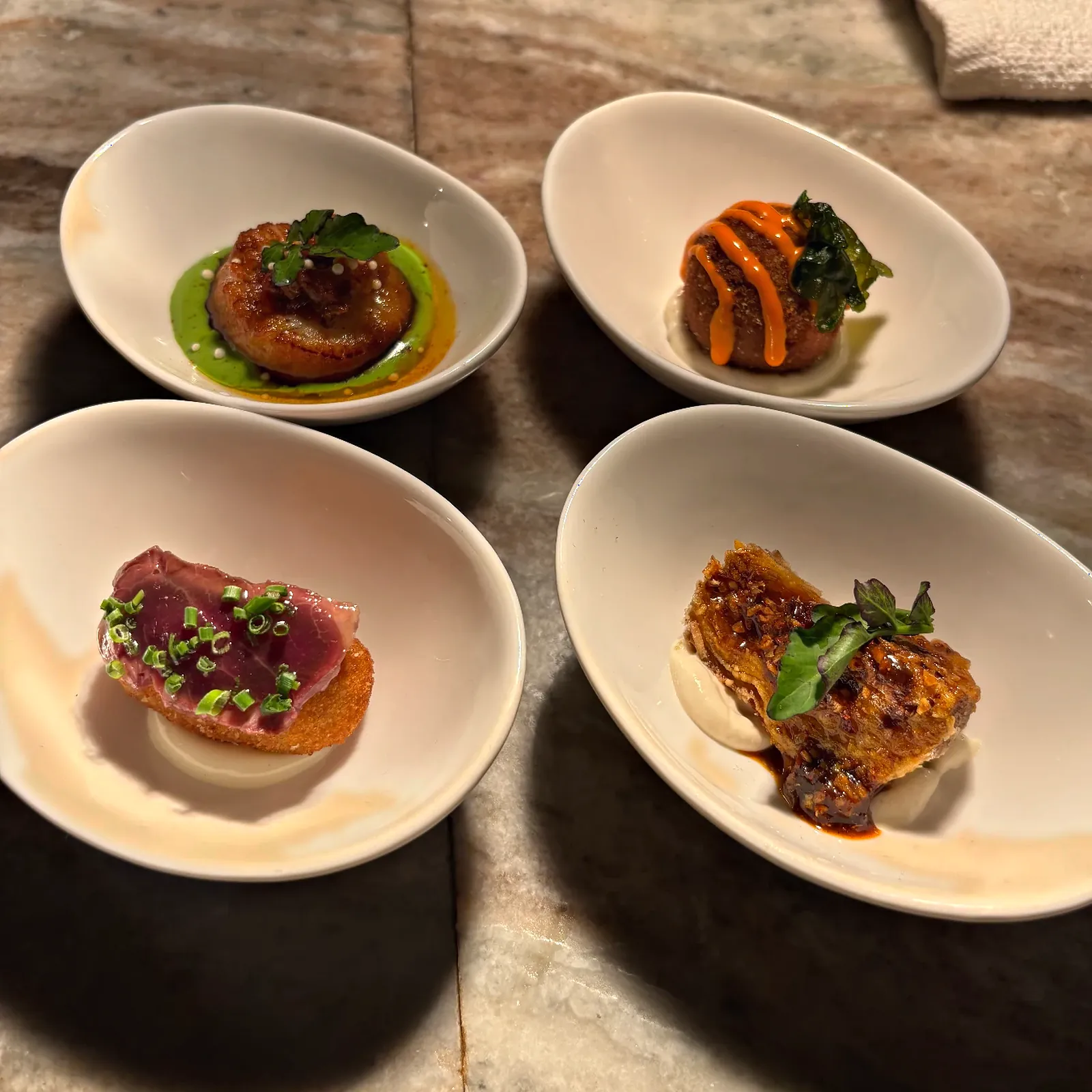 Four canapés plated in white oval dishes for a private celebration