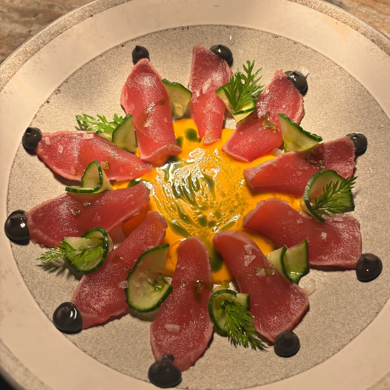 Tuna crudo with dill, cucumber and black olive on speckled stoneware
